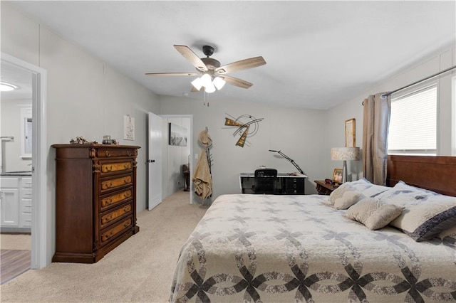 bedroom with ceiling fan, ensuite bathroom, and light colored carpet