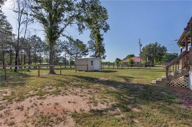 view of yard with a fenced backyard, a shed, an outbuilding, and stairway