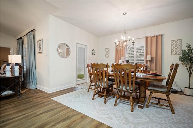 dining room featuring dark wood-type flooring, lofted ceiling, and an inviting chandelier