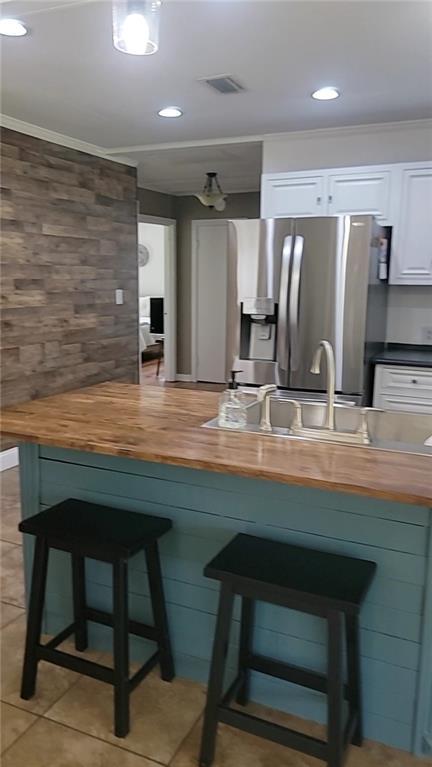 19565 4th St N, Citronelle, AL 36522 - kitchen featuring wooden counters, stainless steel refrigerator with ice dispenser, white cabinetry, a sink, and a kitchen breakfast bar