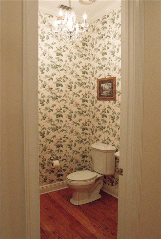 bathroom with ornamental molding, toilet, hardwood / wood-style floors, and a notable chandelier