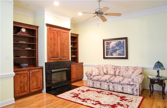 living room with crown molding, ceiling fan, and light hardwood / wood-style flooring