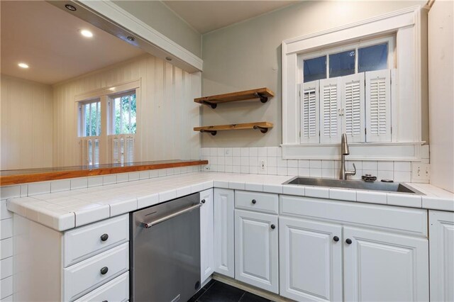 1660 Laurel St, Mobile, AL 36604 - kitchen with stainless steel dishwasher, a sink, white cabinetry, a peninsula, and backsplash