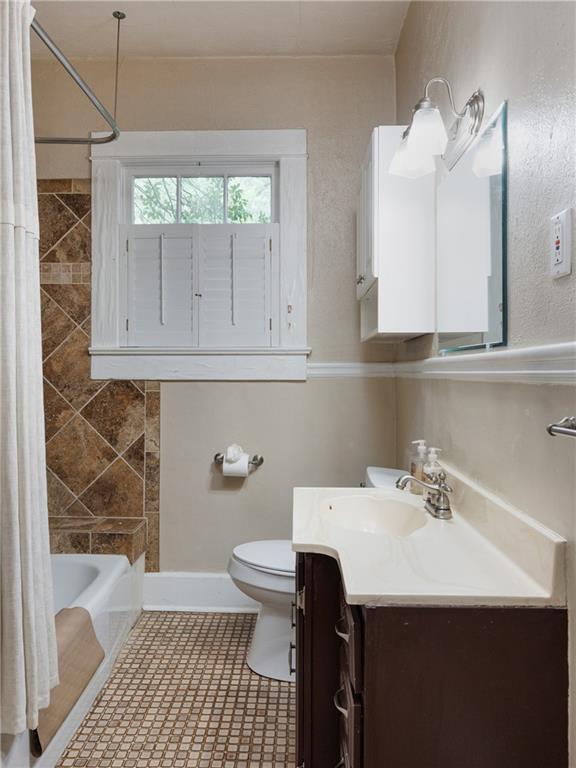 1660 Laurel St, Mobile, AL 36604 - bathroom with vanity, toilet, shower / bathtub combination with curtain, and baseboards