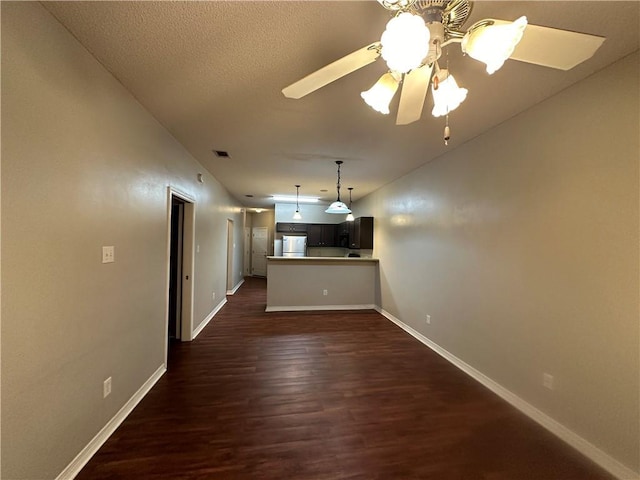 unfurnished living room with dark hardwood / wood-style flooring, a textured ceiling, and ceiling fan