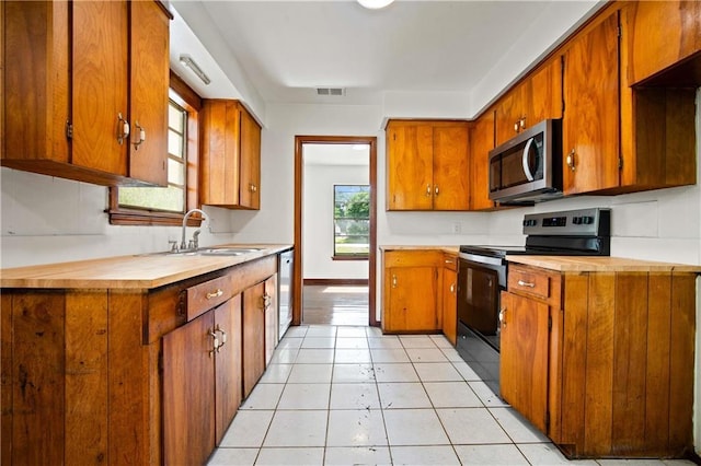 754 Pinemont Dr, Mobile, AL 36609 - kitchen with stainless steel appliances, a sink, brown cabinetry, wood counters, and light tile patterned flooring