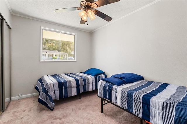 bedroom featuring light carpet, ornamental molding, a textured ceiling, a closet, and baseboards