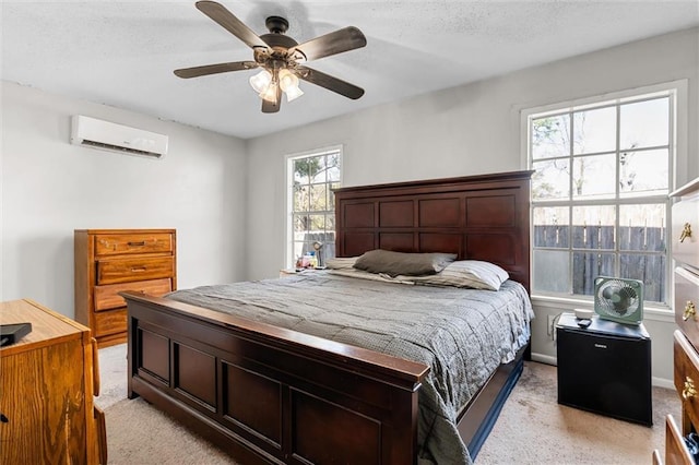 bedroom featuring a textured ceiling, light carpet, a ceiling fan, and a wall mounted AC