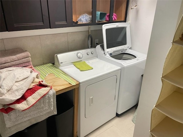 laundry area with washer and clothes dryer and light tile patterned floors