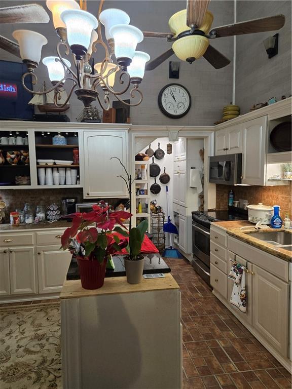 kitchen featuring appliances with stainless steel finishes, a sink, decorative backsplash, and open shelves