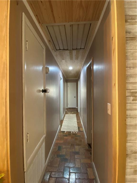 hall with brick floor, attic access, and wood walls