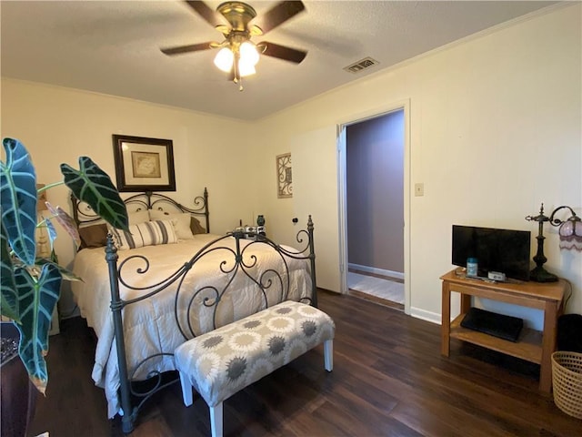 bedroom featuring visible vents, ornamental molding, wood finished floors, baseboards, and ceiling fan