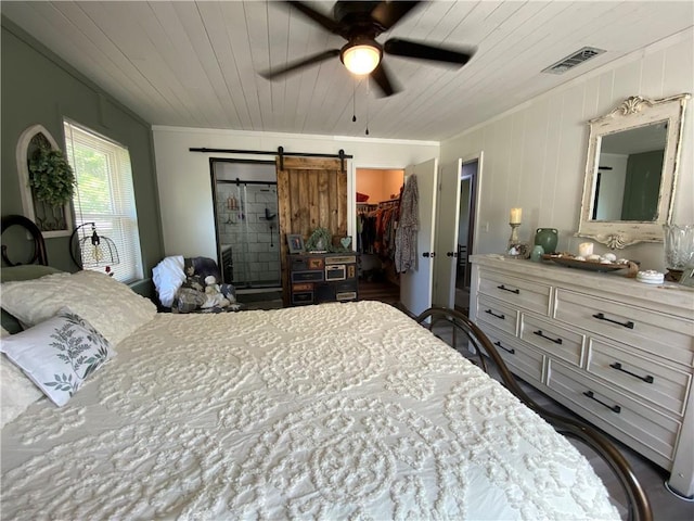 bedroom with visible vents, a closet, ornamental molding, a walk in closet, and a barn door