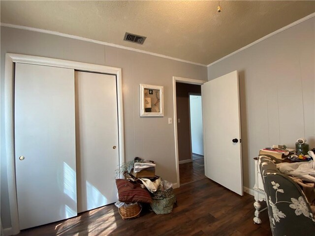 bedroom with crown molding, dark wood-style flooring, a textured ceiling, and visible vents