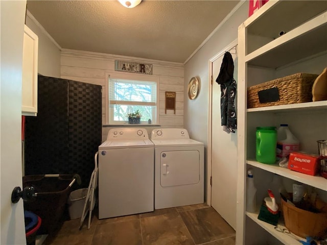 laundry room featuring laundry area, wood walls, ornamental molding, washer and clothes dryer, and a textured ceiling