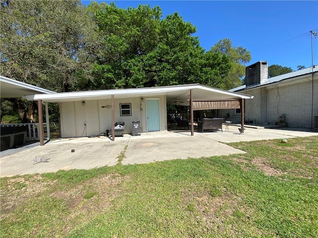 back of property featuring a lawn, board and batten siding, a chimney, and a patio area