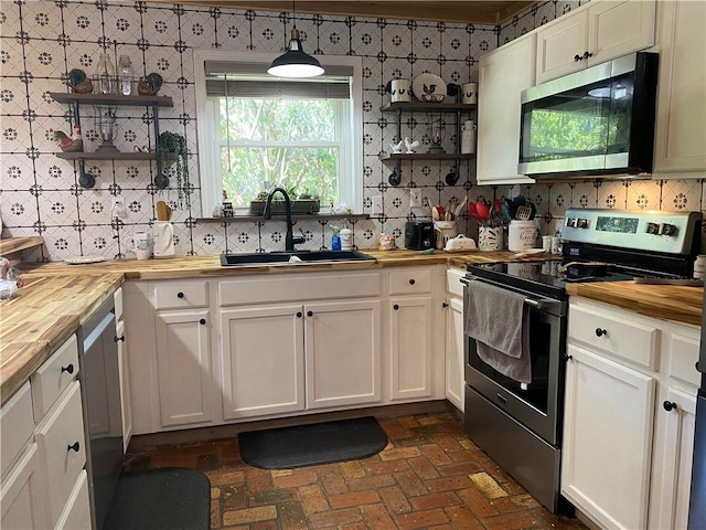 kitchen with stainless steel appliances, wood counters, a sink, and open shelves