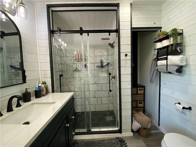 full bathroom featuring wooden walls, vanity, toilet, a shower stall, and wood finished floors
