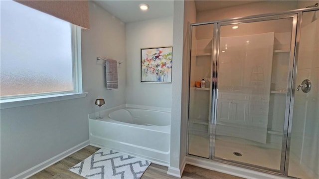 bathroom with a garden tub, a shower stall, and wood finished floors