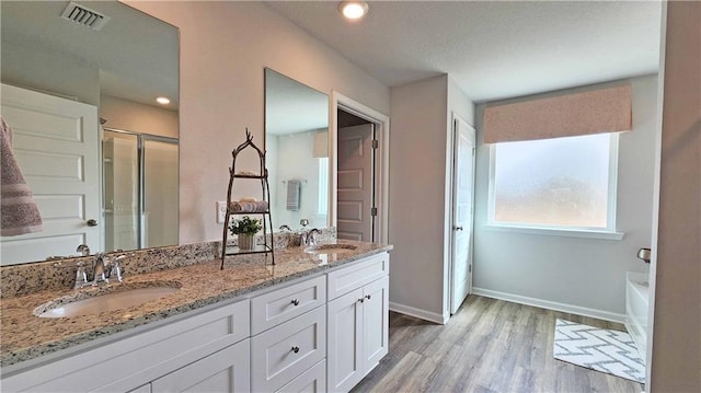 full bathroom featuring wood finished floors, visible vents, a sink, and a stall shower