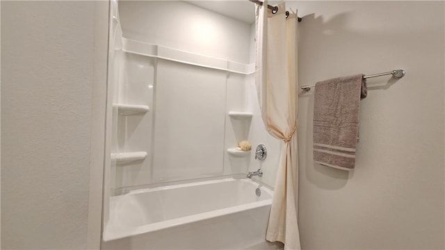 bathroom featuring a textured wall and shower / tub combo