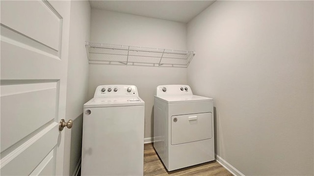 laundry area featuring washing machine and dryer, baseboards, laundry area, and light wood-type flooring