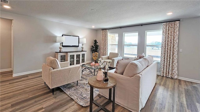 living area with recessed lighting, wood finished floors, a textured ceiling, and baseboards