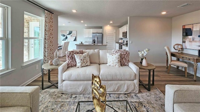 living room with visible vents, baseboards, wood finished floors, and recessed lighting