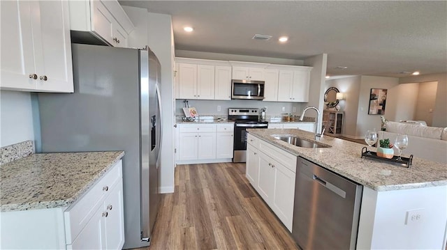kitchen with light wood-style flooring, a sink, visible vents, white cabinetry, and appliances with stainless steel finishes