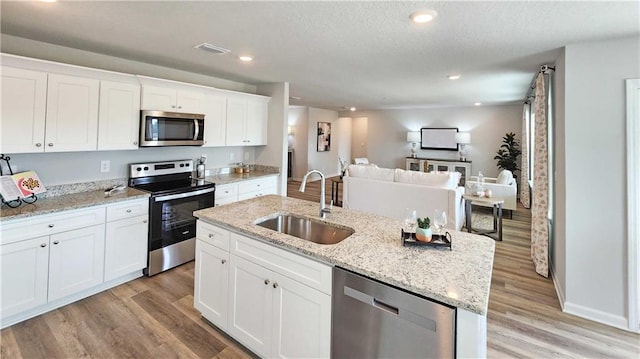 kitchen featuring a sink, open floor plan, light wood-style floors, appliances with stainless steel finishes, and visible vents