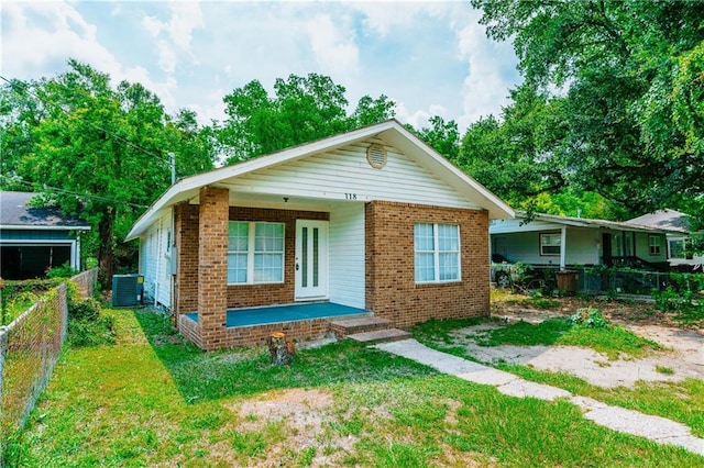 bungalow-style home featuring cooling unit, covered porch, and a front yard