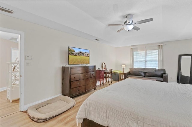 bedroom with baseboards, a raised ceiling, visible vents, and light wood finished floors