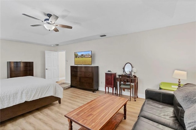 bedroom featuring a ceiling fan, baseboards, visible vents, light wood-style flooring, and a raised ceiling