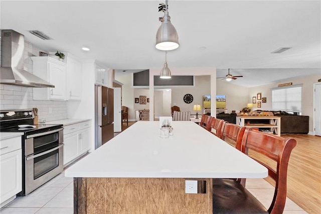 kitchen featuring double oven range, light countertops, fridge with ice dispenser, white cabinetry, and wall chimney exhaust hood