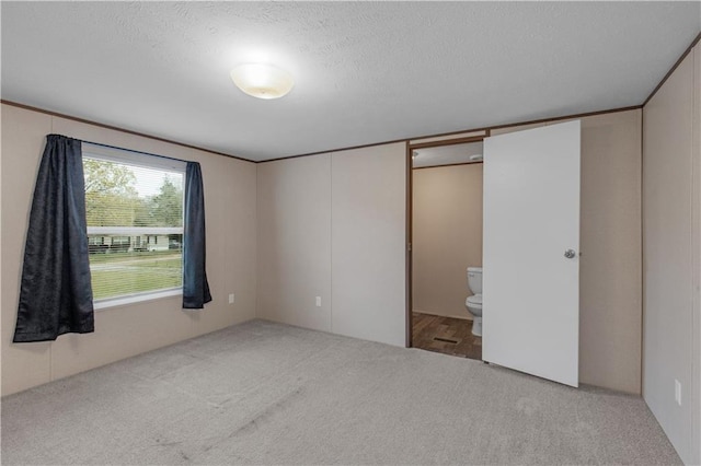unfurnished bedroom featuring carpet flooring, a textured ceiling, and connected bathroom