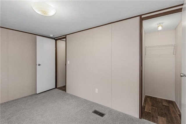 unfurnished bedroom with carpet, visible vents, a spacious closet, and a closet