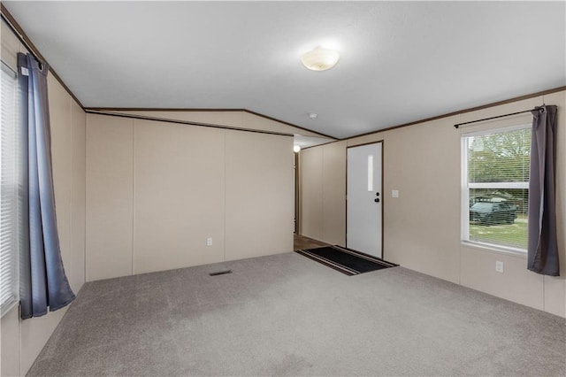 empty room with lofted ceiling, carpet flooring, and visible vents