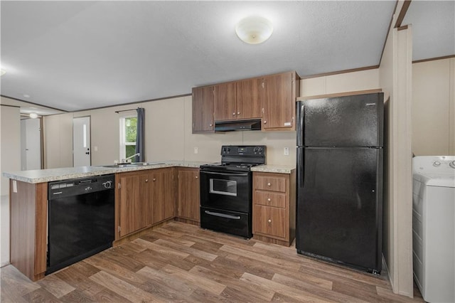 kitchen with black appliances, washer / dryer, light wood finished floors, a peninsula, and under cabinet range hood
