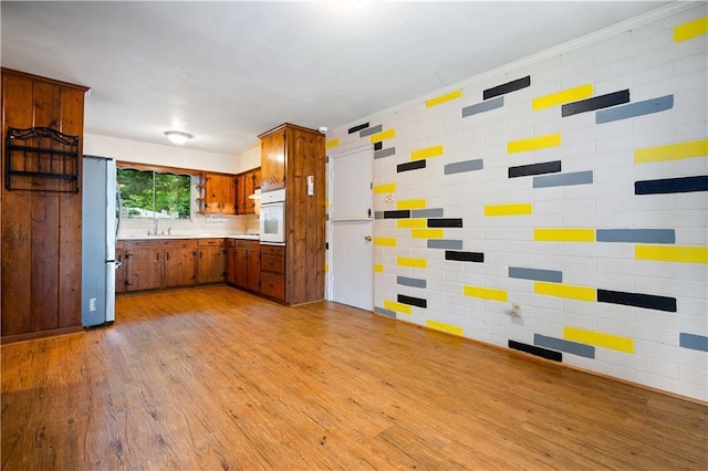 4359 Montclair Cir E, Mobile, AL 36693 - kitchen with freestanding refrigerator, white oven, brown cabinets, light wood-style flooring, and light countertops