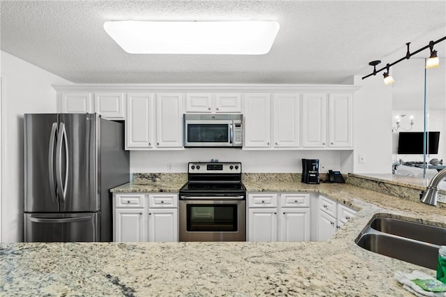 527 Beach Club Trl Unit D1103, Gulf Shores, AL 36542 - kitchen featuring stainless steel appliances, white cabinetry, a textured ceiling, and light stone countertops