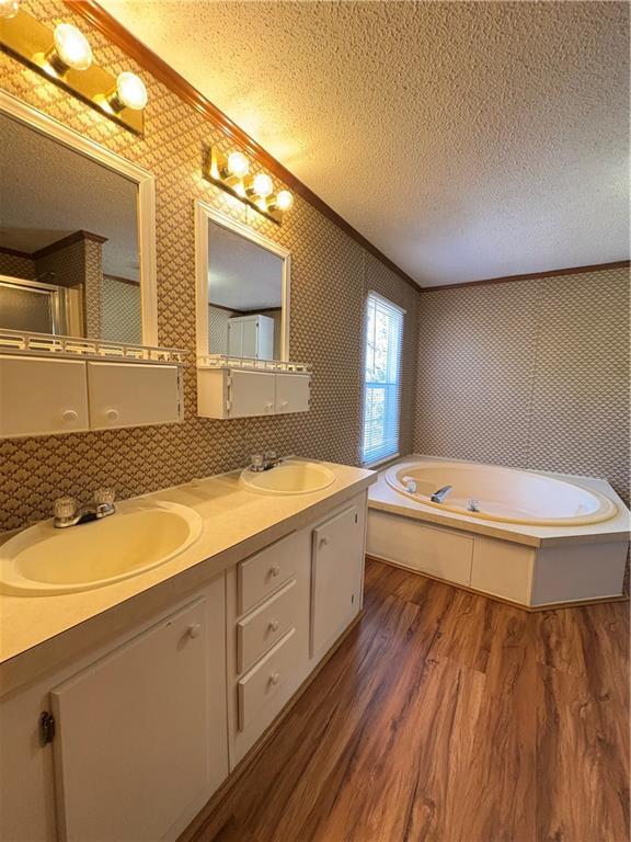 bathroom featuring crown molding, vanity, hardwood / wood-style floors, and a textured ceiling