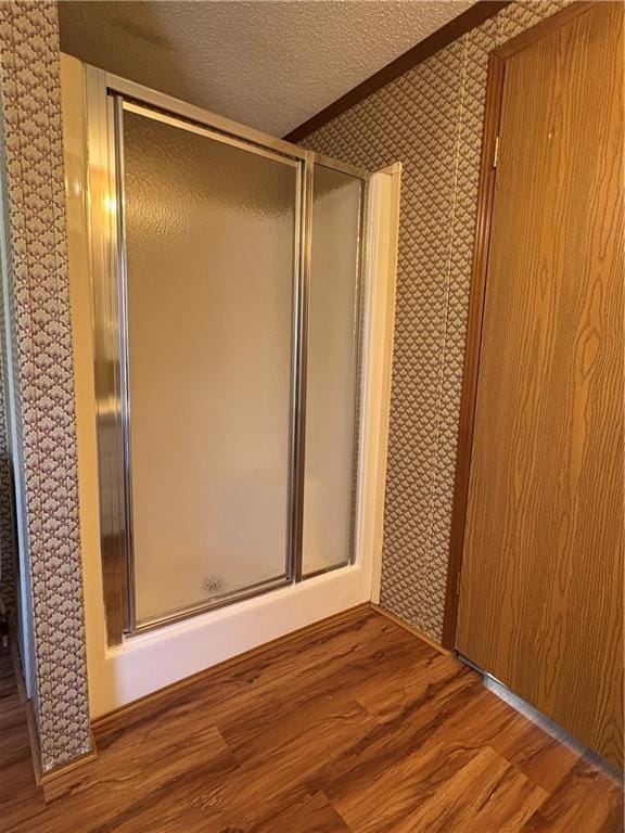 bathroom with hardwood / wood-style floors, a textured ceiling, and walk in shower