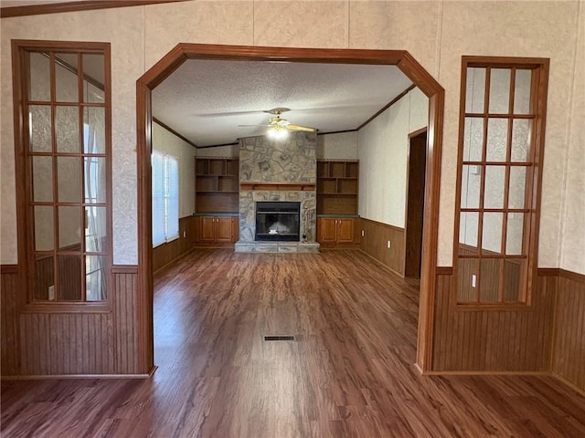 unfurnished living room with built in shelves, ornamental molding, dark hardwood / wood-style floors, and a textured ceiling