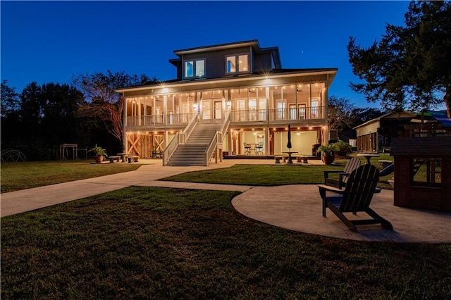 back house at night featuring a lawn, a patio area, and covered porch