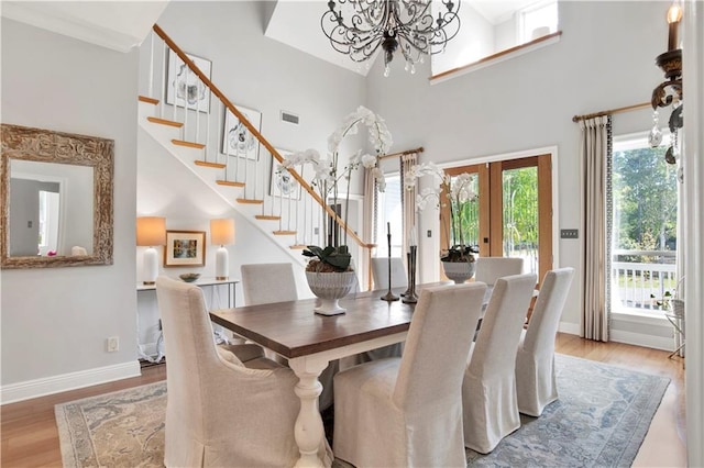 dining area featuring french doors, an inviting chandelier, a high ceiling, and hardwood / wood-style flooring