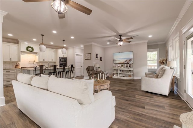 living room featuring ornamental molding, ceiling fan, and dark wood-type flooring