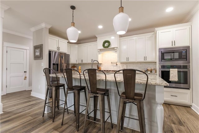 kitchen featuring light stone countertops, white cabinetry, pendant lighting, and stainless steel appliances