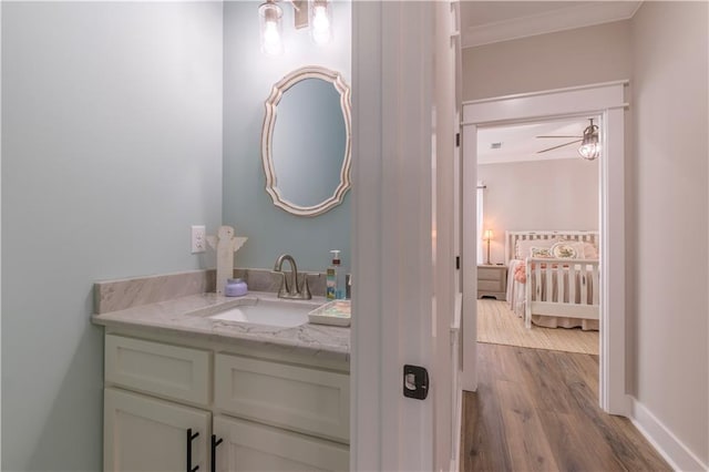 bathroom with ceiling fan, crown molding, vanity, and hardwood / wood-style flooring