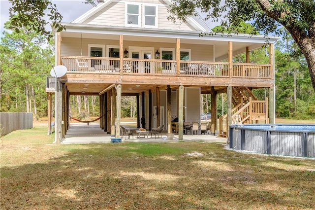 back of property with a swimming pool side deck, a patio, and a lawn