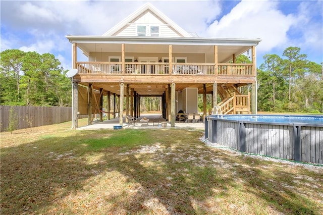 rear view of property featuring a yard, a pool side deck, and a patio